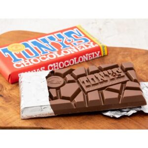 Tony's Chocolonely chocolate bar with broken chocolate pieces displayed on a wooden table.